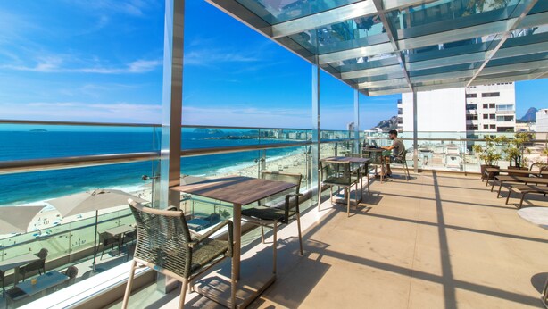 Ein Balkon mit Glasgeländern mit Blick auf einen Strand und das Meer.