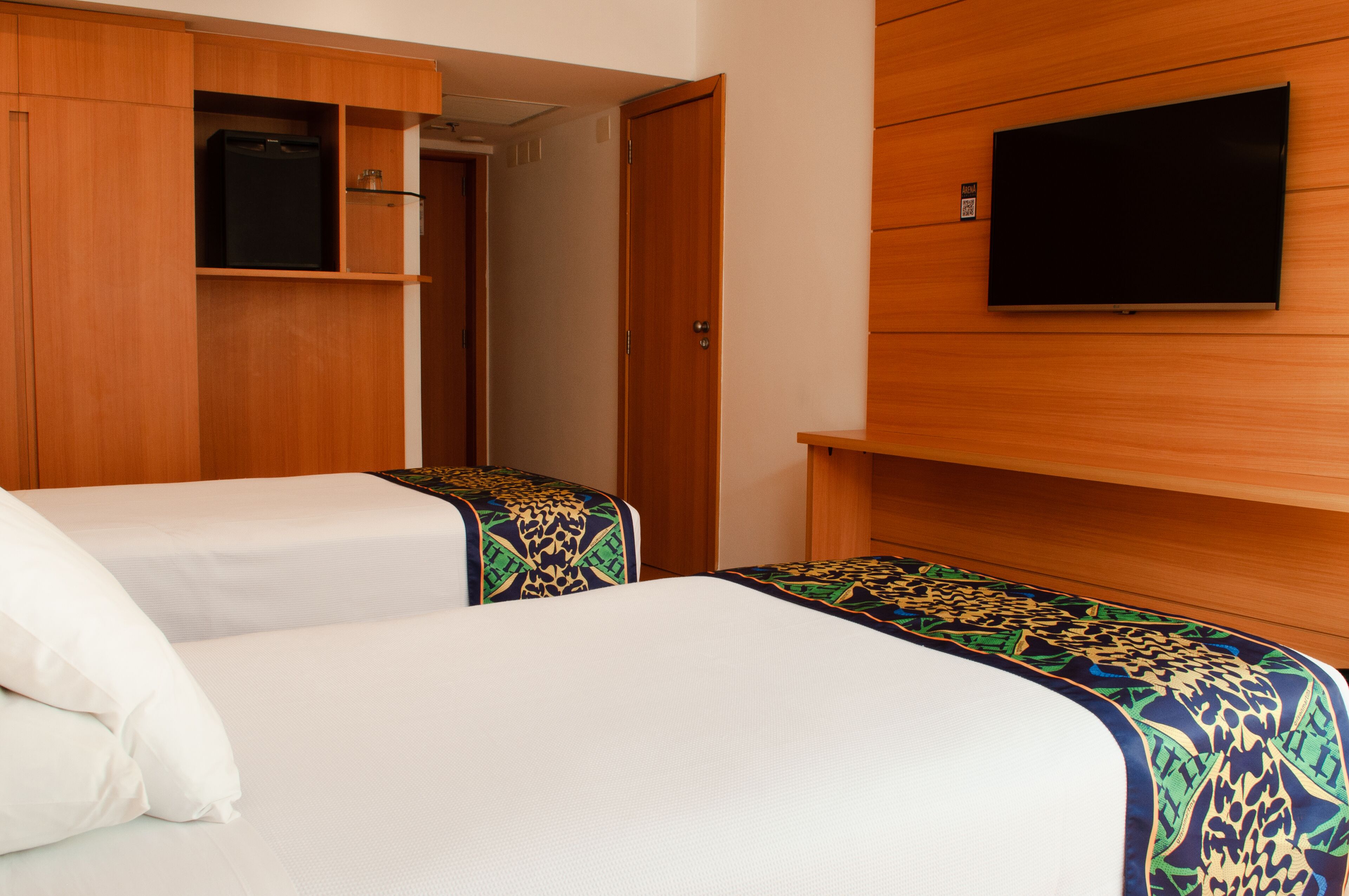 Habitación de hotel con dos camas, televisión y armario.