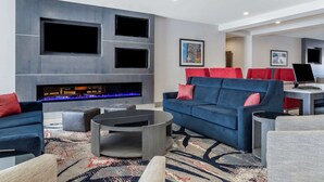 Un salon moderne avec une cheminée, des canapés bleus et un téléviseur à écran plat fixé au mur.
