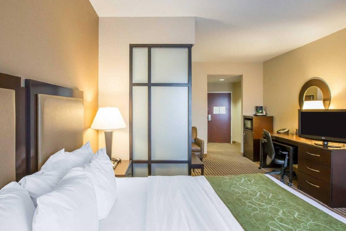 Een hotelkamer met een bed, bureau, stoel, televisie en een deur naar de badkamer.