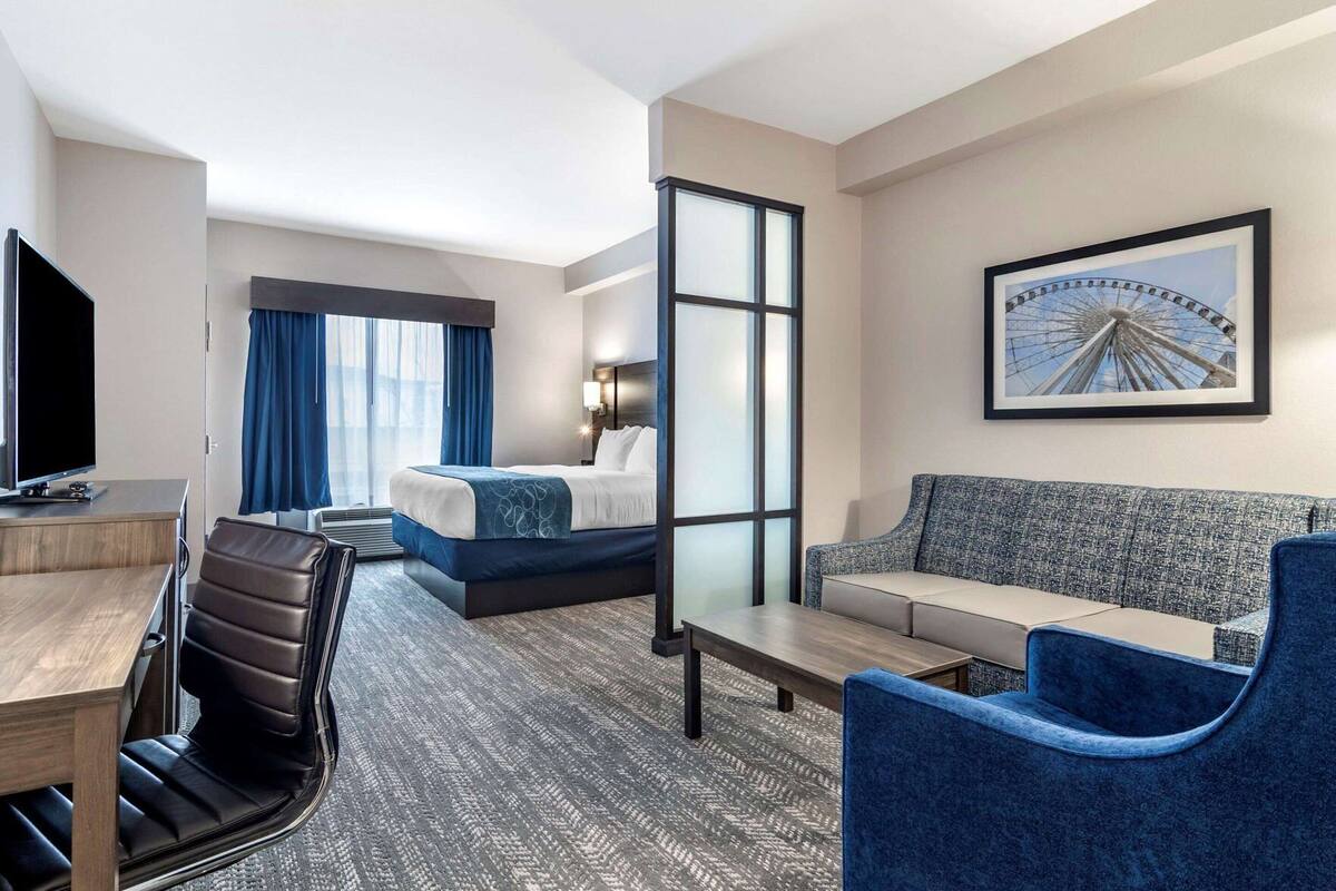 Een hotelkamer met een bed, een bureau, een stoel, een bank en een groot raam.