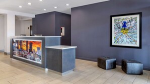 Un espace d’accueil au design moderne, comprenant un comptoir de réception, une carte encadrée accrochée au mur et deux tabourets en métal.