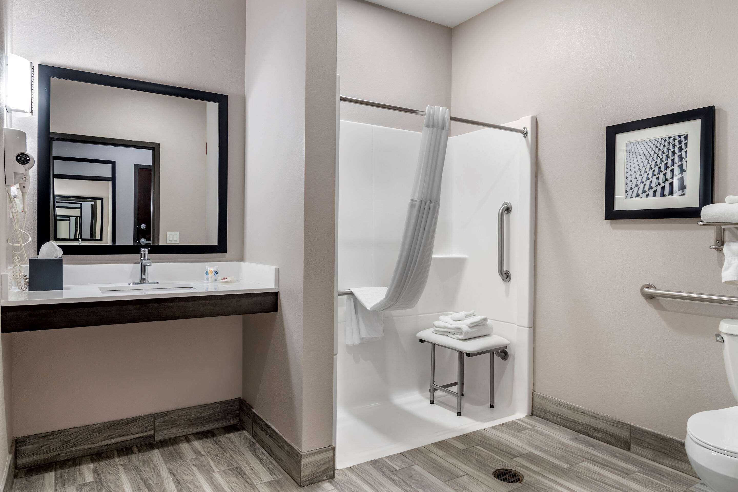 A modern bathroom with a shower, a sink with a towel rack, and a toilet.