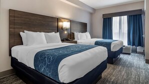 Une chambre d’hôtel avec deux lits, une table de chevet avec une lampe et une grande fenêtre avec des rideaux.