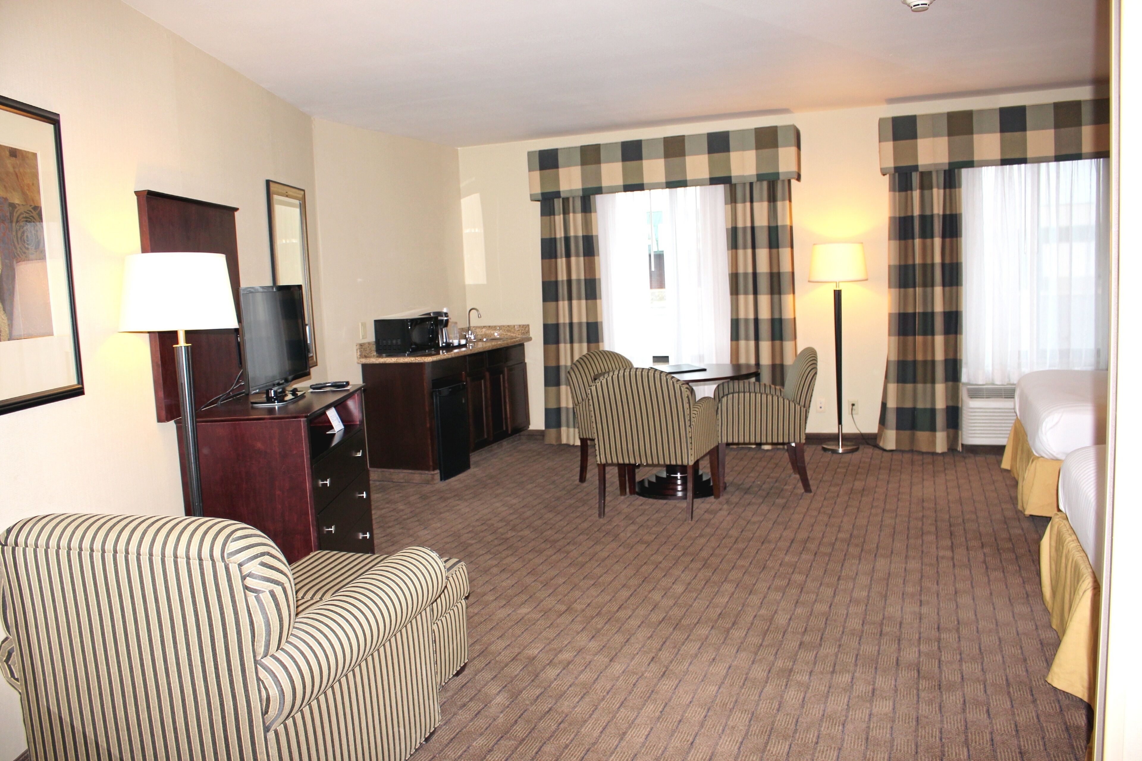 Ein Hotelzimmer mit Essbereich, Fernseher, Schreibtisch und Bett.