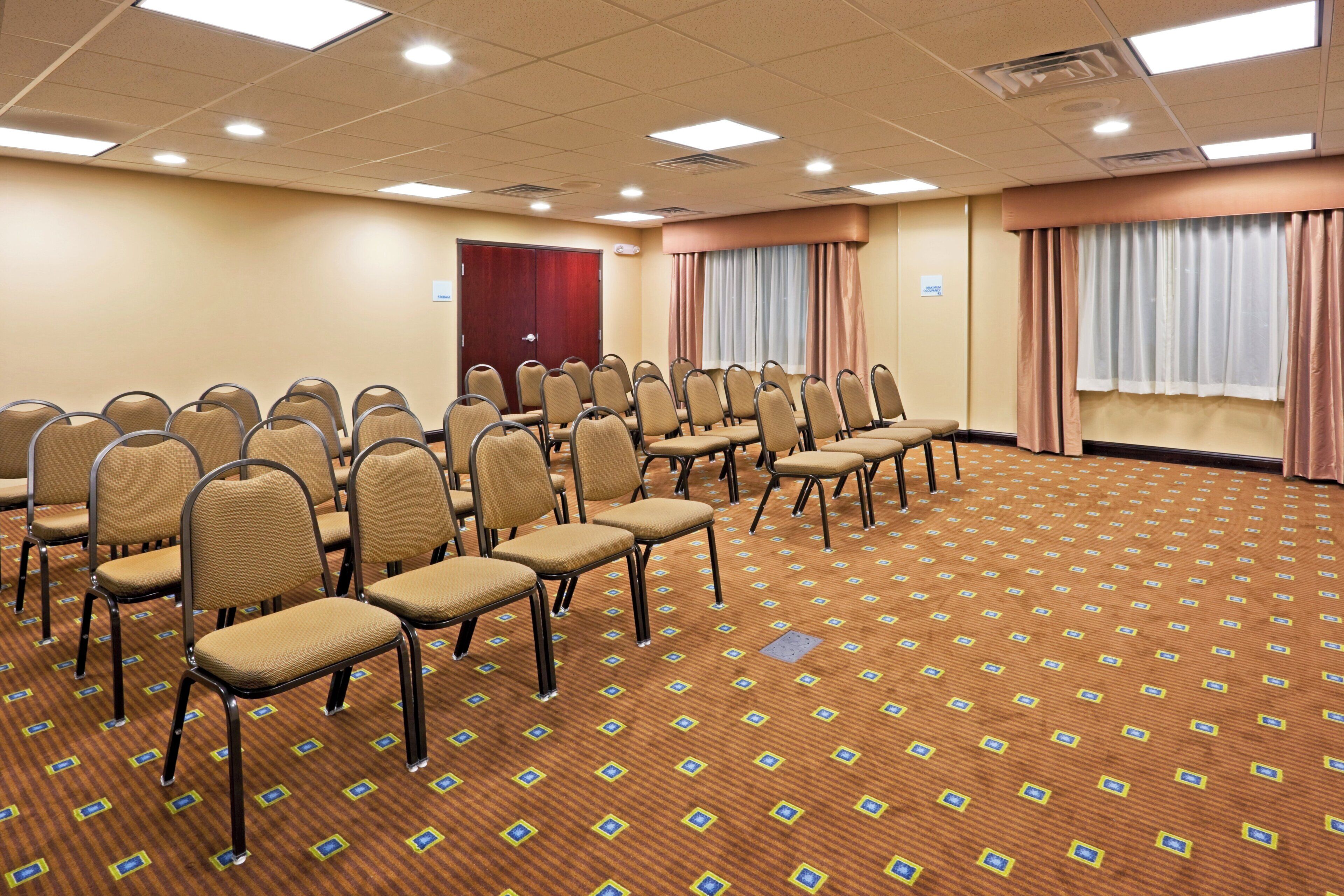 Une salle de conférence avec des rangées de chaises, un placard de rangement et une grande porte.