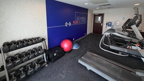 A gym with exercise equipment, a wall with motivational text, and a door.