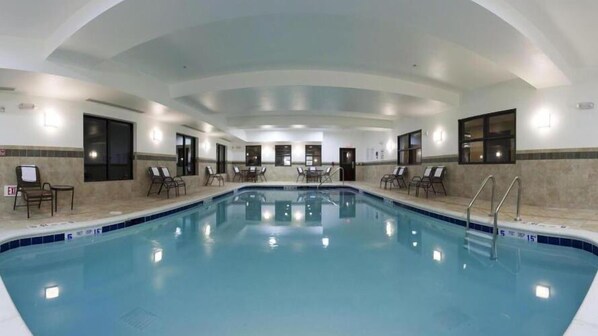An indoor swimming pool with multiple lanes, surrounded by lounge chairs and a tiled wall. - Holiday Inn Express Hotel & Suites Syracuse North - Cicero by IHG (Cicero)