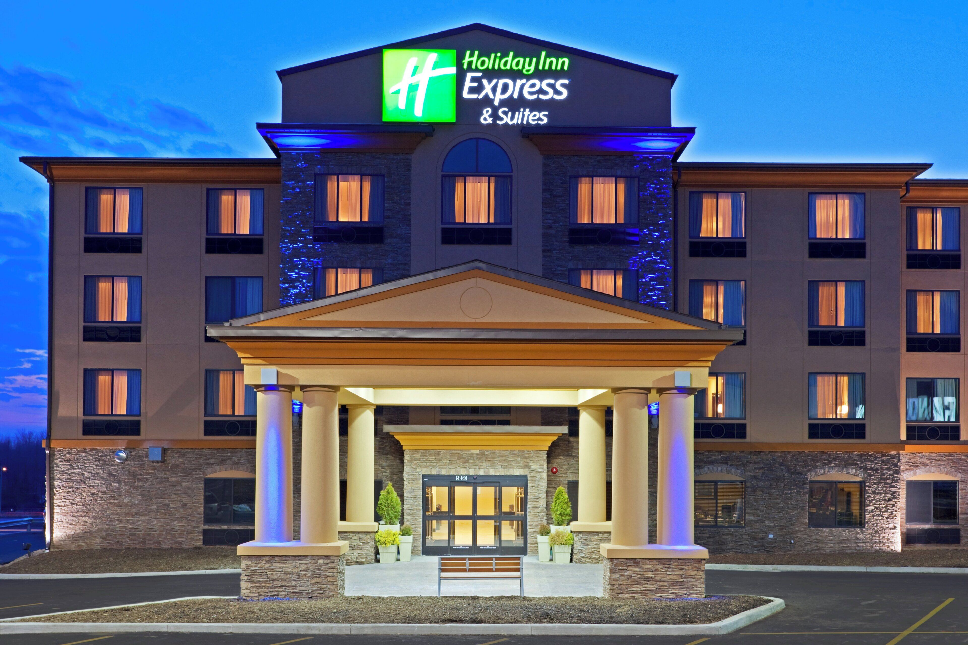 Een Holiday Inn Express & Suites gebouw met een centrale ingang, meerdere ramen en een gevel van natuursteen.