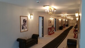 A hallway with a black leather bench, a red console table, and a black sofa. - The Village At Pocono (Blakeslee)