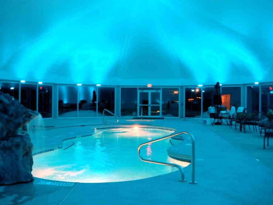 Een binnenzwembad, ligstoelen bij het zwembad