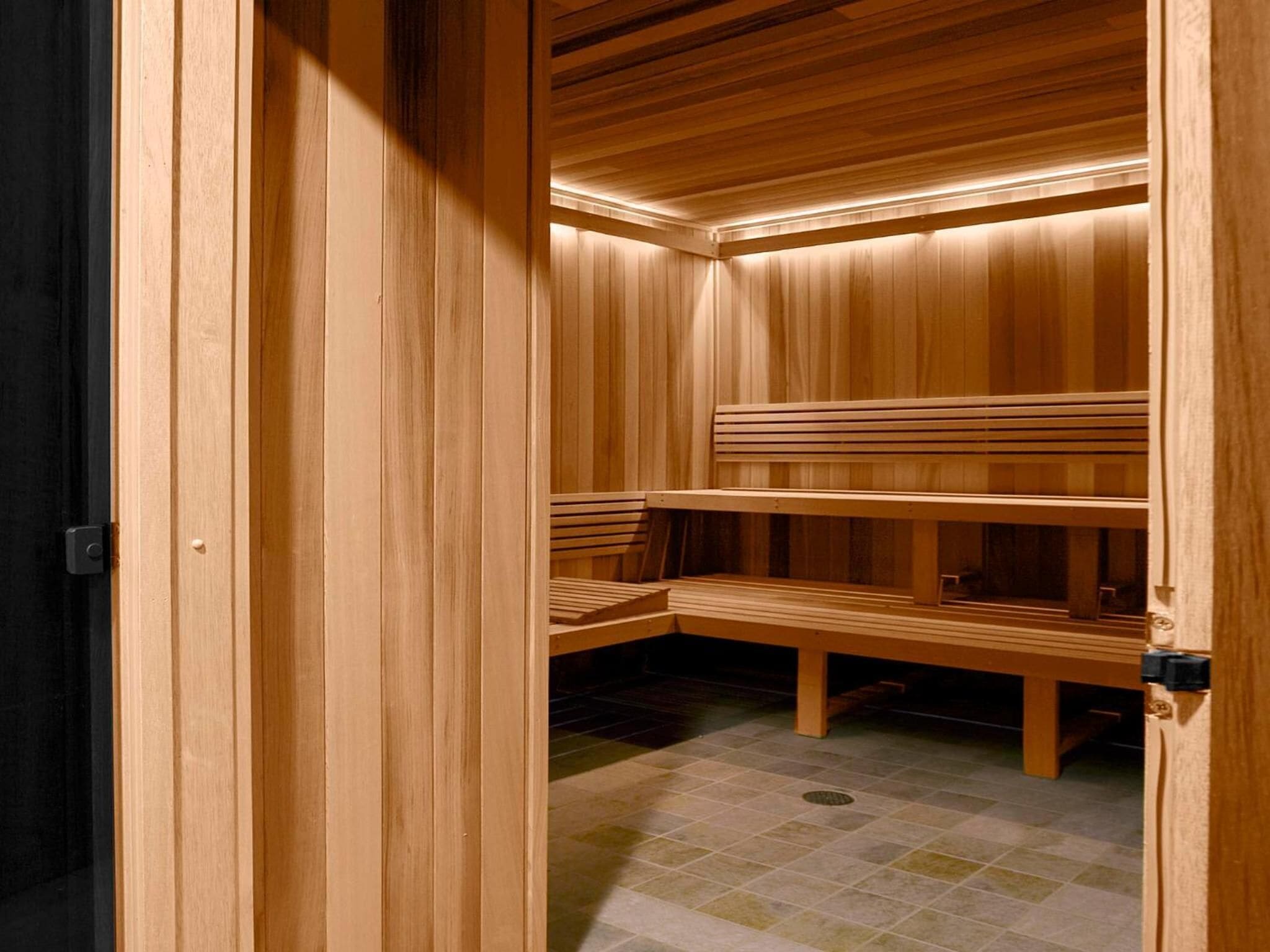 Una sauna de madera con bancos y suelo de baldosas.