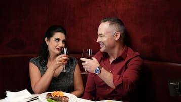 A couple seated at a table with a meal, in a room with red upholstered seating.