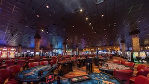 Een casino met meerdere blackjack tafels, gokkasten en een groot roulette rad.