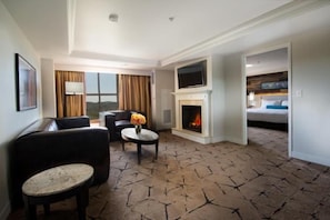 Habitación de hotel con chimenea, televisor, sofá y vistas al exterior.