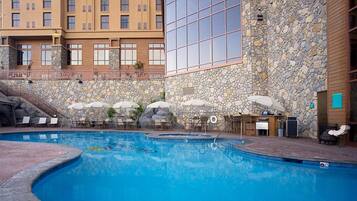Relax by the pool surrounded by lounge chairs and umbrellas.