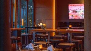 A restaurant with wooden tables and chairs, candles, and a television screen in the background. - Qube Hotel Bergheim (Heidelberg)