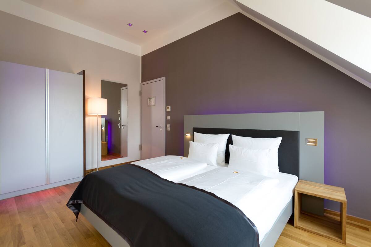 Un dormitorio moderno con una cama grande, una mesita de noche de madera y un armario.