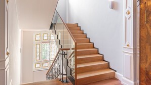 A staircase with wooden steps and glass railings, leading to a room with white walls and a decorative window. - Qube Hotel Bergheim (Heidelberg)
