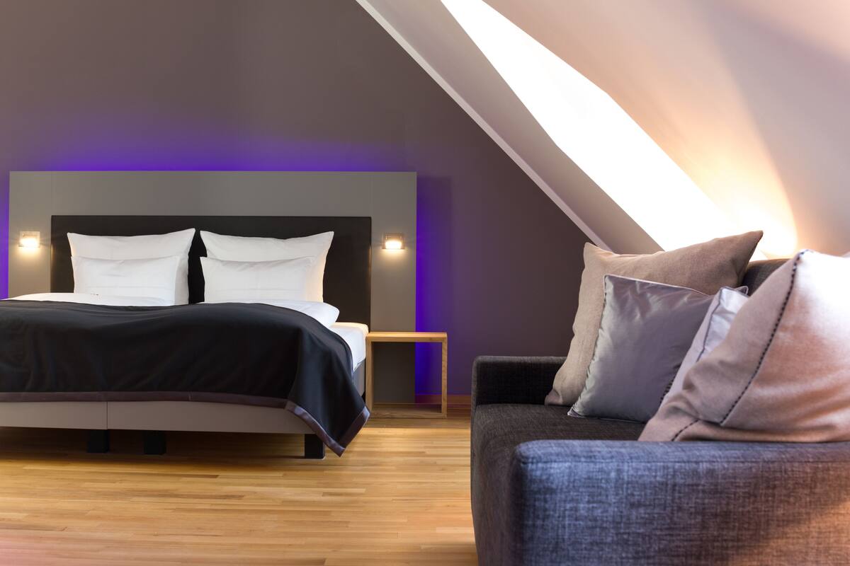 Un dormitorio moderno con cama, mesita de noche y sofá.