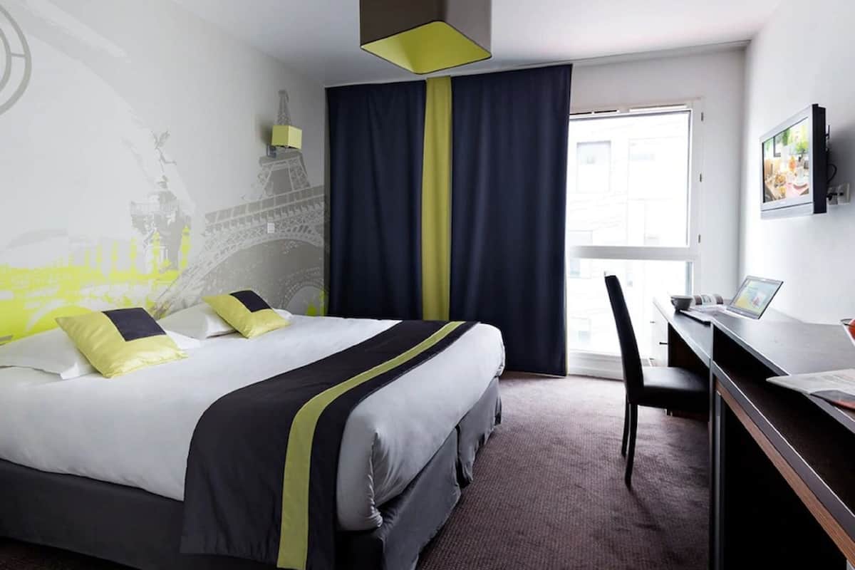 Ein Hotelzimmer mit Bett, Schreibtisch mit Laptop, Stuhl, großem Fenster mit Vorhängen und Wandgemälde.