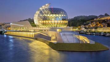 A modern architectural structure with a large dome and a waterfront setting.