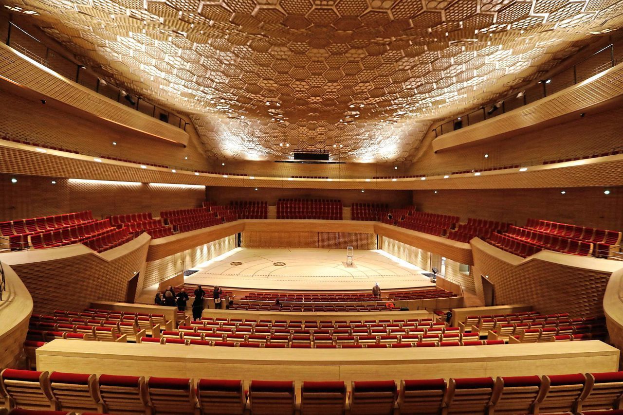 A large, modern auditorium with tiered seating and a geometric ceiling design.