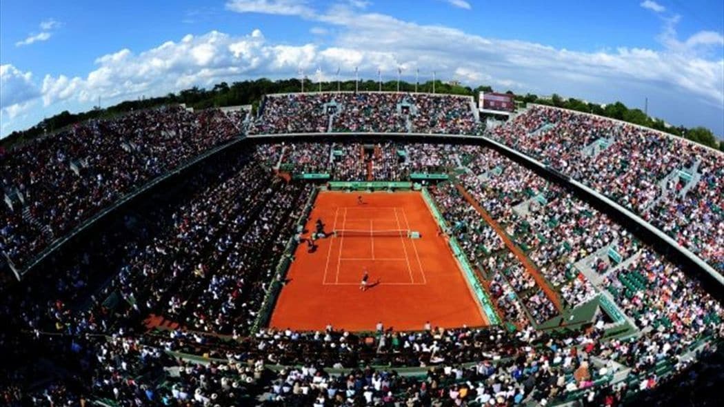 Een tennistadion met meerdere zitverdiepingen en een centraal veld.