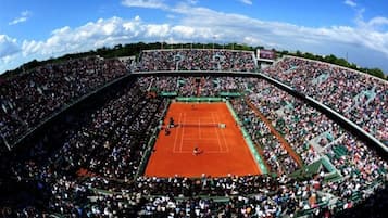 Een tennistadion met meerdere zitverdiepingen en een centraal veld.