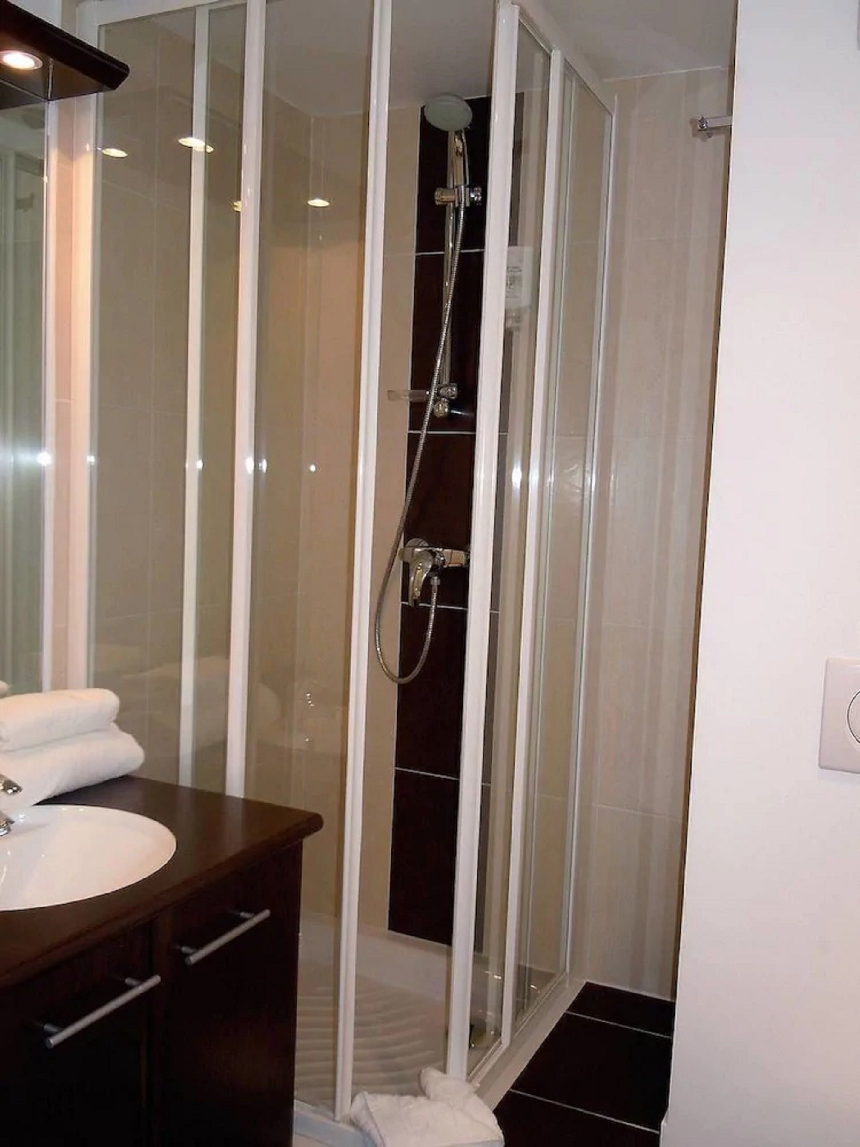 Un baño moderno con cabina de ducha de vidrio, tocador con lavabo y espejo.