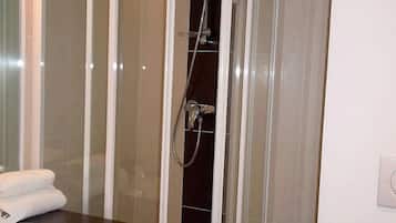 A modern bathroom with a glass-enclosed shower, a vanity with a sink, and a mirror.
