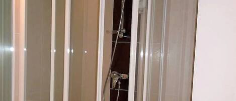 A modern bathroom with a glass-enclosed shower, a vanity with a sink, and a mirror.