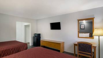 A hotel room with two beds, a TV, a desk, a chair, a lamp, and a wardrobe.