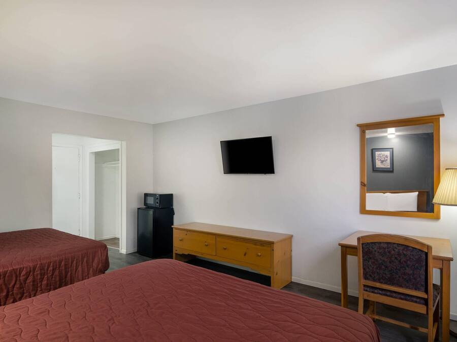 A hotel room with two beds, a TV, a desk, a chair, a lamp, and a wardrobe.
