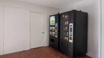 Una habitación con dos máquinas expendedoras, una puerta blanca y suelo de baldosas.