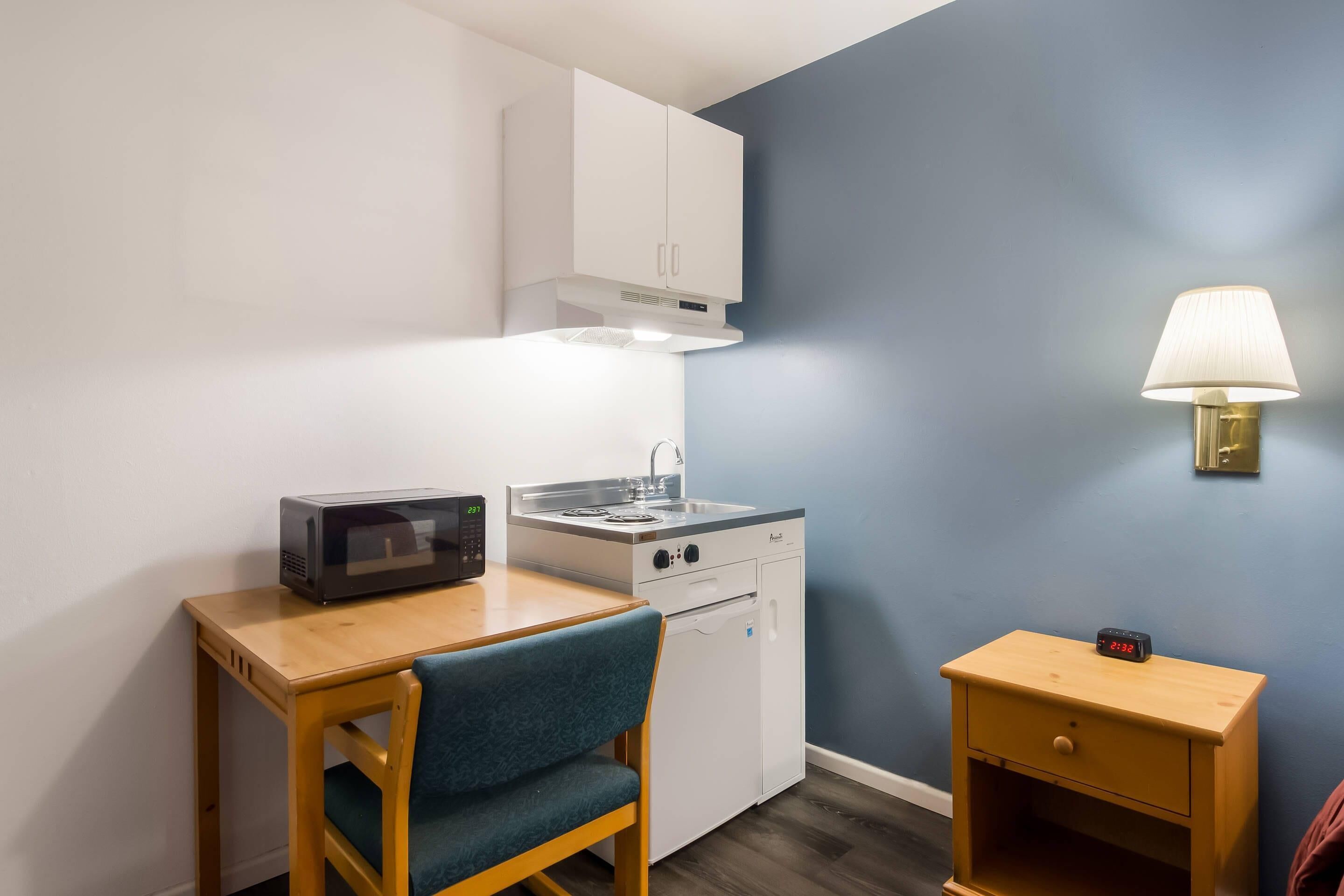 Una kitchenette compacta con microondas, estufa y alacenas.