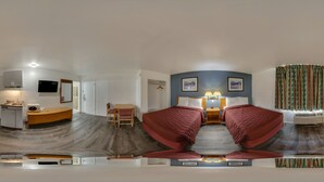 Ein Panoramablick auf ein Hotelzimmer mit Küche, Essbereich und Schlafzimmer mit zwei Betten.