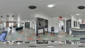 Eine Hotelhalle mit Empfangstresen, Sitzgelegenheiten und einem Steinboden.