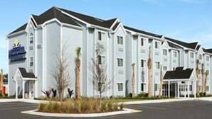 A multi-story hotel with a symmetrical facade, large windows, and a central entrance. - Microtel Inn & Suites by Wyndham Spring Hill/Weeki Wachee (Spring Hill)