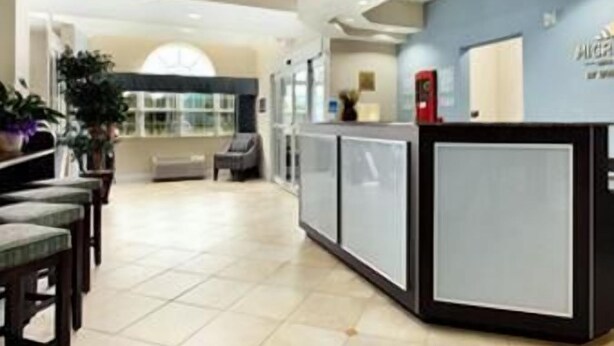 A reception area with a counter, seating, and a large window. - Microtel Inn & Suites by Wyndham Spring Hill/Weeki Wachee (Spring Hill)