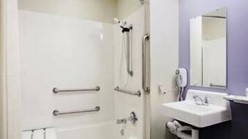 A bathroom with a bathtub, a sink, a mirror, and a towel rack.