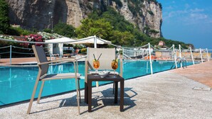 A poolside area with lounge chairs and a table with drinks, overlooking a cliff and pool. - Le Ancore (Vico Equense)