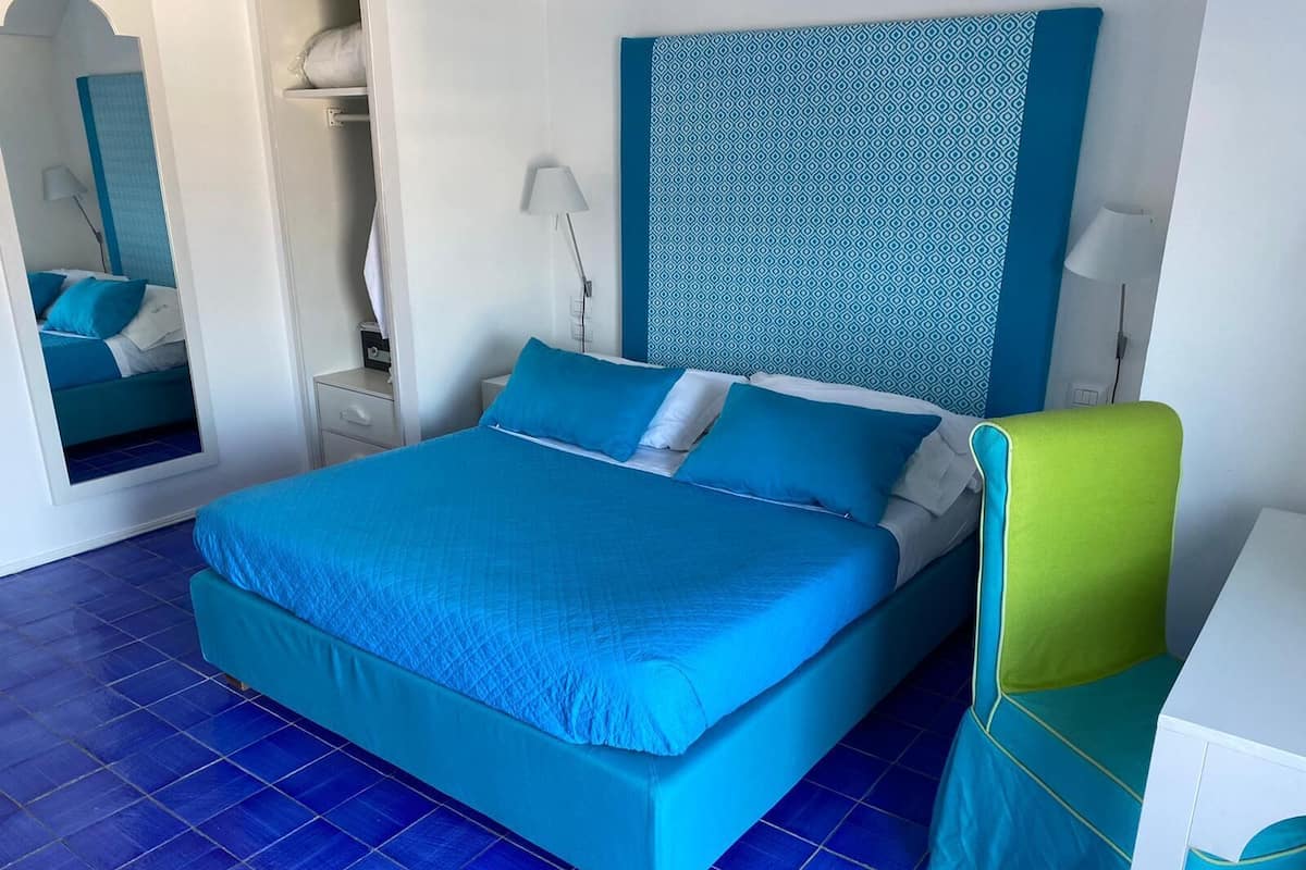 Un dormitorio con una cama grande, una mesita de noche, una silla y un espejo.