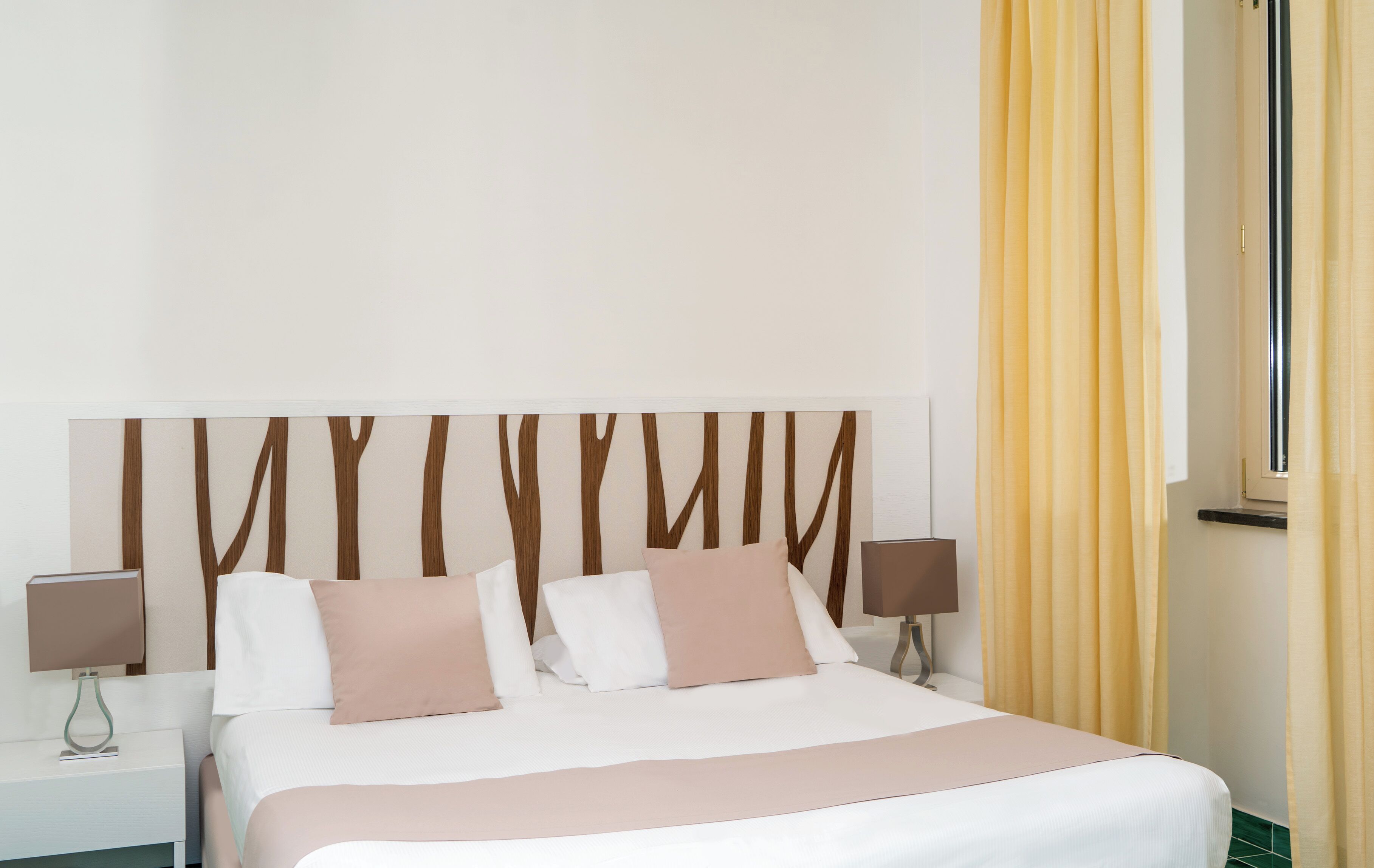 Une chambre d’hôtel avec un grand lit, deux tables de chevet et une tête de lit moderne.