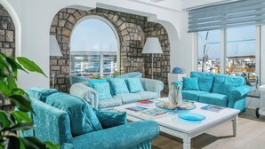 A modern living room with two teal sofas, a white coffee table, and a stone archway. - Le Ancore (Vico Equense)