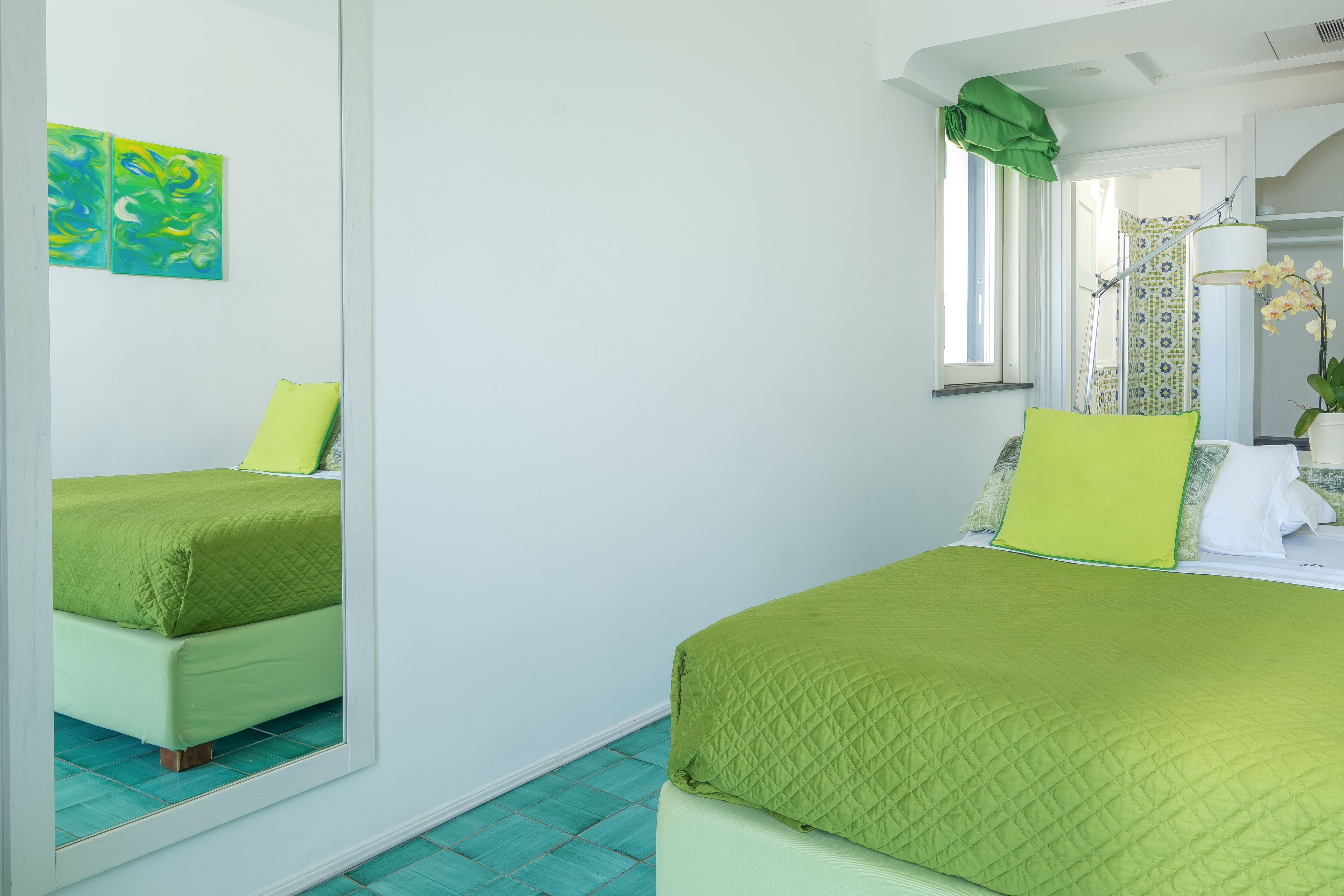 A bedroom with a bed, a mirror, and a window.