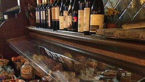 A bakery display with various baked goods and a wine selection. - Armanac De Toubie (Arnad)