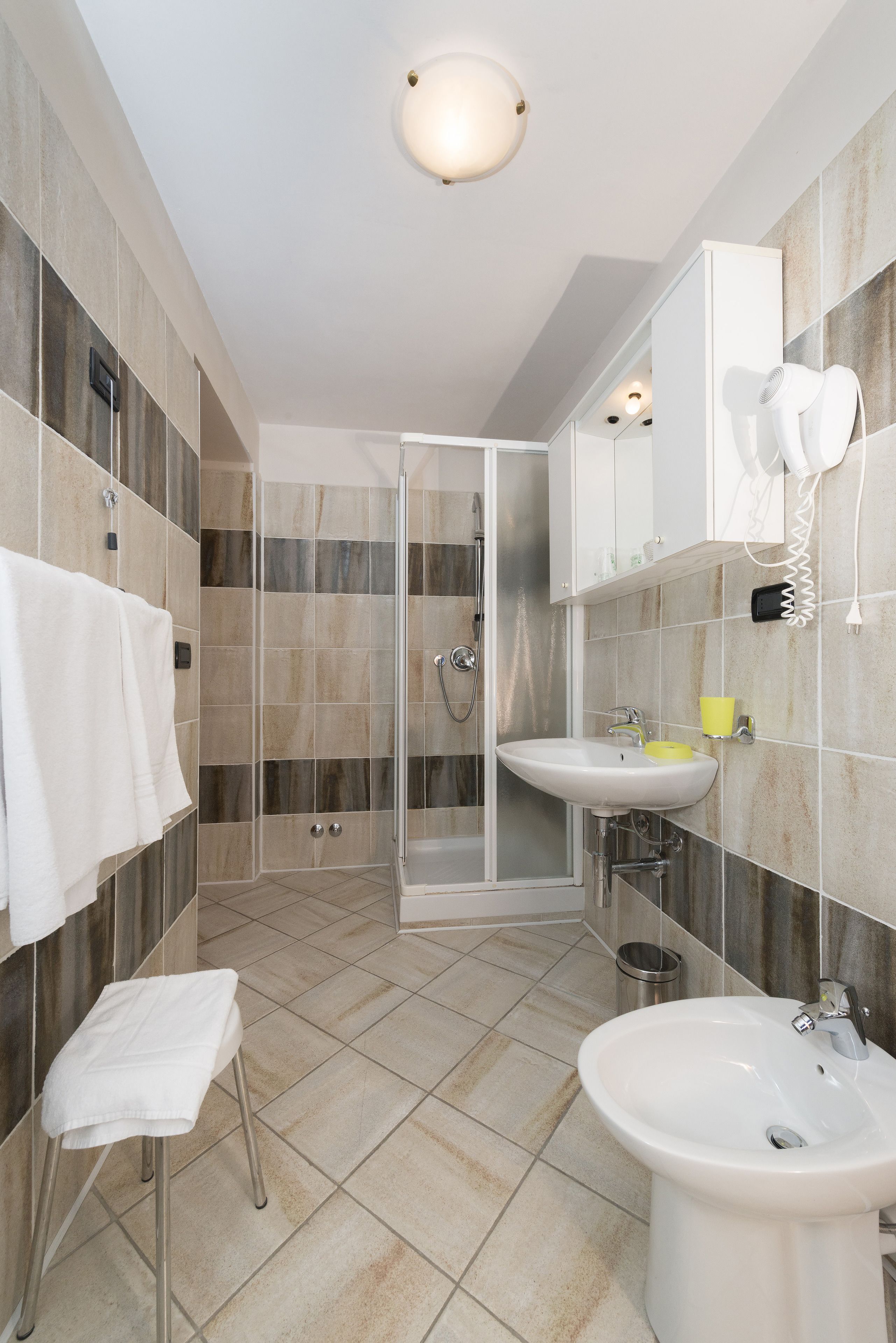 Un bagno moderno con doccia vetrata, lavandino e mobile vanità dotato di asciugacapelli.