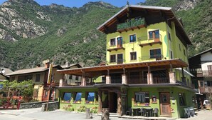 A multi-story hotel with balconies and a mountain backdrop. - Armanac De Toubie (Arnad)