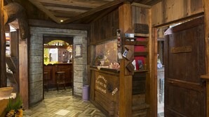 A rustic interior with wooden walls, a stone archway, and a bar area with stools. - Armanac De Toubie (Arnad)